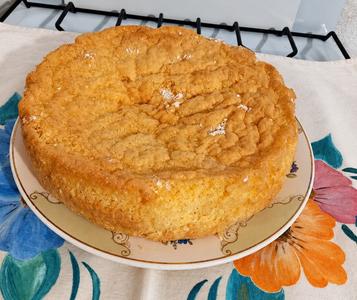 Bizcochuelo de coco entero, dorado y servido sobre un plato
